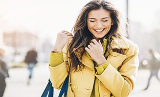 Happiness Beautiful young woman smiling and walking outdoors in the city, with sunlight and copy space